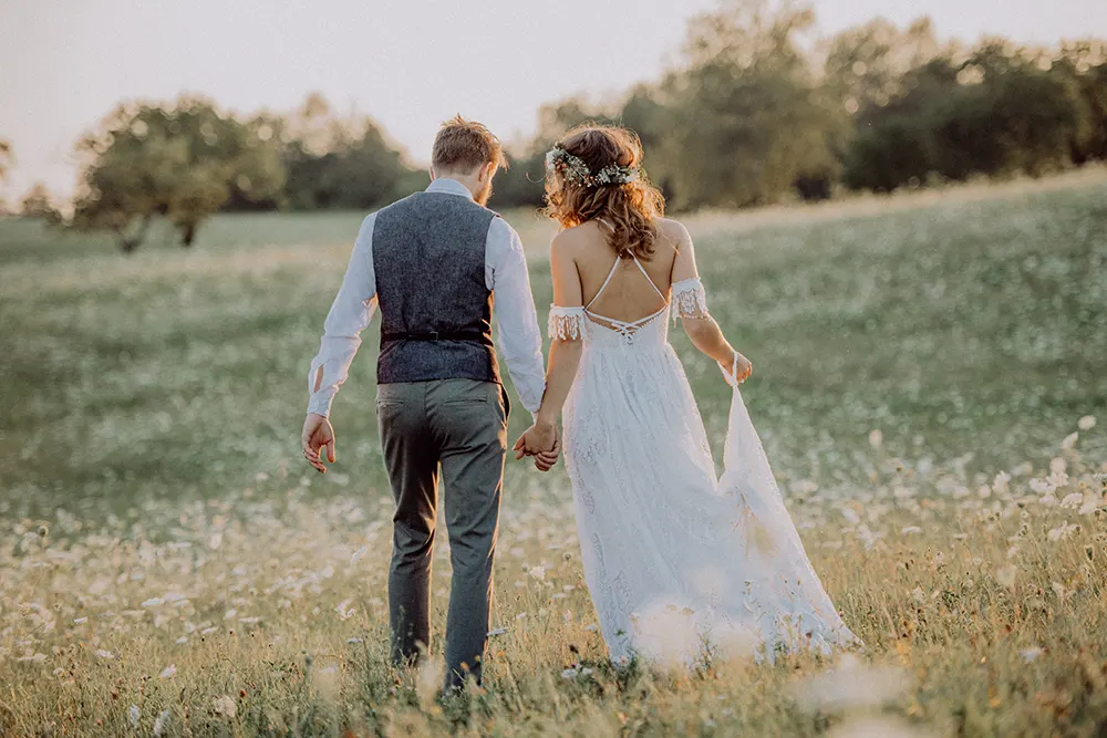 romantic couple walking in field at sunset utc